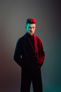 Young man wearing trench coat in studio.