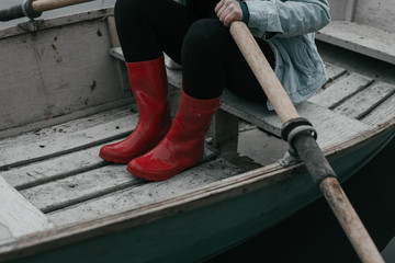 woman wearing red rubber boots in leaky rowboat