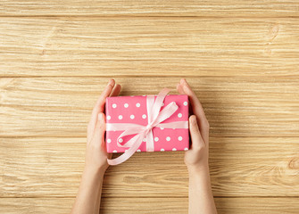 gift box in the hands on a wooden background top view