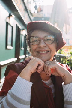 Portrait of a cheerful senior woman with French beret, sun flare