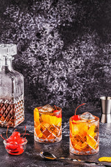 Old fashioned cocktail with cherries and orange twist.
