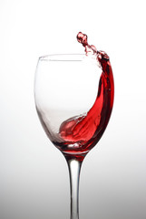 Splash of red wine in a crystal glass on a white background close-up