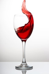 Splash of red wine in a crystal glass on a white background close-up