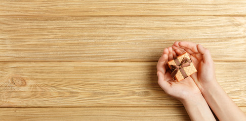 gift box in the hands on a wooden background top view