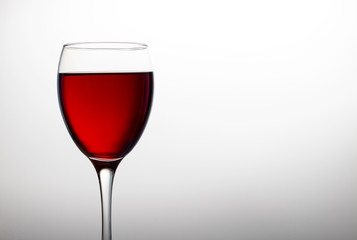 Wineglass with red wine close-up isolated on light background, copy space