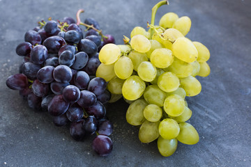Bunches of ripe green and blue grapes close-up on a blue shabby concrete background