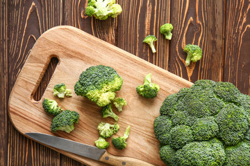 Cutting board with fresh broccoli cabbage and knife on wooden table