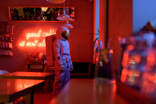 Lonely astronaut standing in modern cafe