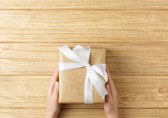 gift box in the hands on a wooden background top view