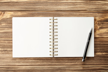 notebook with pen and blank sheets on wooden table