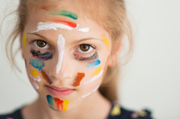 beautiful portrait of little caucasian girl face with colorful art painting on her with multicolor paint