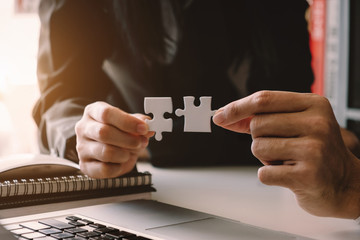 Business solutions and success concept. Businessman hand connecting jigsaw puzzle at office in...