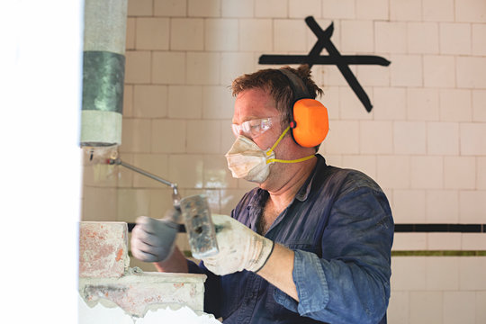 Demo Day - Male tradesman hard at work demolishing a brick wall