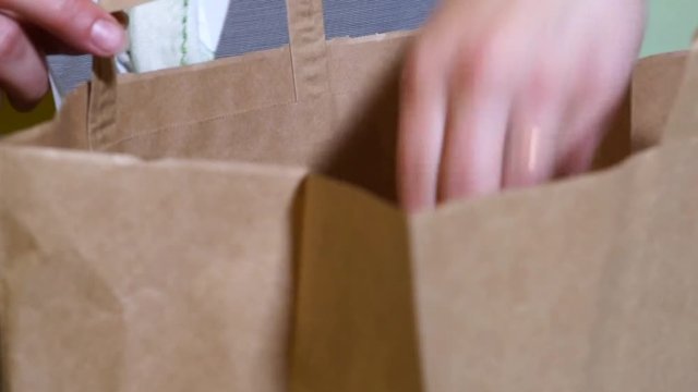 Restaurant staff filling brown paper bag with takeout meal, close up shot