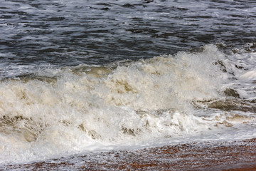 Storm at sea, big foamy waves breaking on shore