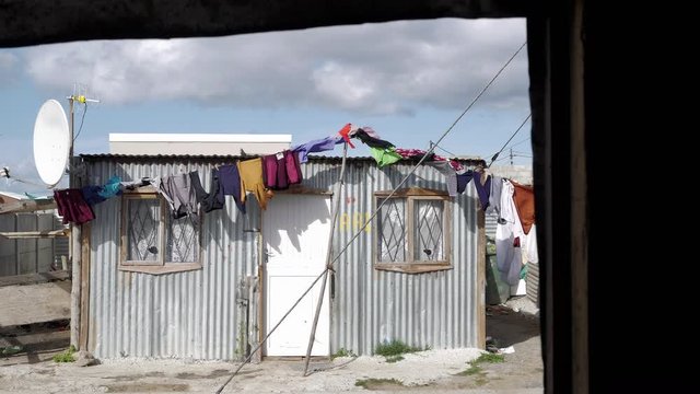 Washing flapping in front of shack in township, shot from within opposite shack