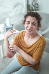Curly red-haired woman having much pain after car accident