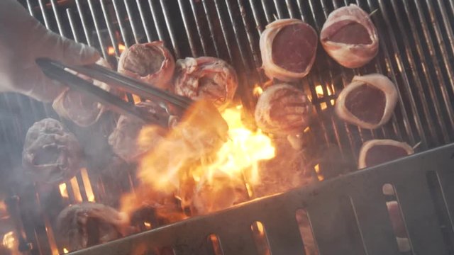 A filet mignon grilled while bacon burning fat, in slow motion.