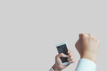 A person with a smartphone is surprised or happy.  Good business results, winning a lottery, watching sports or selling, etc.　スマートフォンを手に持った人が驚いているまたは、喜んでいる様子。ビジネスの好結果、宝くじが当たる、スポーツ観戦、安売りなど