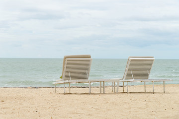 empty two beach chairs on a beautiful beach at sunny day - vacation in summer time