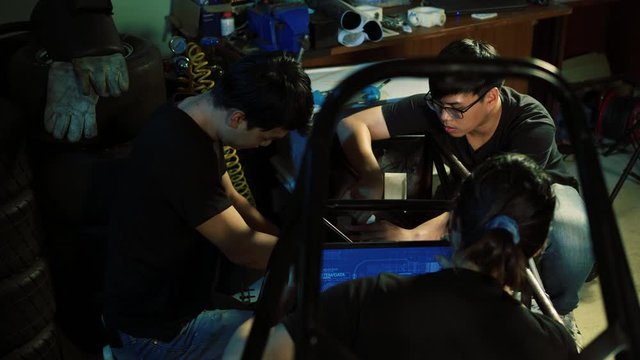 Asian engineer students are updating software with assembling and testing electric vehicles at the university. Concept of configuration, technological developments and renewable energy.
