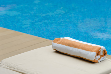 Roll soft towel on a sun bed near a swimming pool.