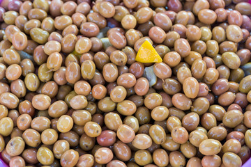 Green olives stacked on a surface as background.