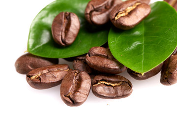 coffee beans with two green leaves on a white background, isolate. concept: freshness of coffee beans.
