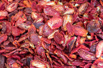 Dried tomato vegetables stacked on a surface as background.