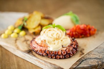 Roasted octopus BBQ with Baked potato. Wooden plate. Restaurant menu