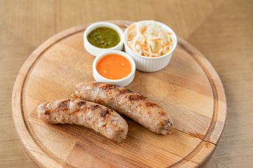 Grilled sausages. Serving on a wooden Board. Barbecue restaurant menu, a series of photos of different meats. Pickled cabbage and two sauces