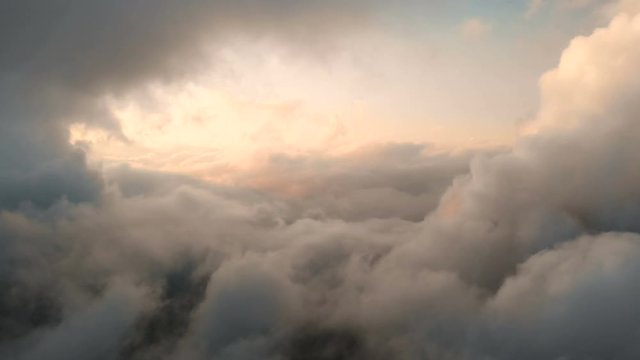 Aerial view flying through cumulus thunderclouds at sunset. Gold colored sunset cloudiness in high contrast. Real sky. The concept of dreams and weather forecast