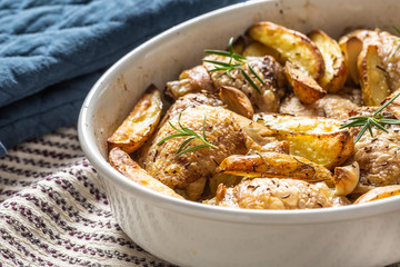 Chicken legs roasted with american potatoes in baking dish