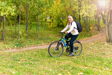 Fototapeta premium A woman on a Bicycle rides on the road in the city Park