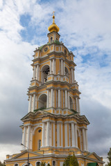 Fototapeta premium The bell tower of the Novospassky Monastery against a cloudy sky. The photo was taken in early autumn, in the afternoon, under natural light