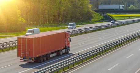 LKW mit Container auf der Autobahn im Sonnenlicht