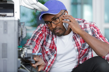 technician repairing photocopier and talking on telephone