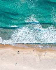Antenne von Menschen, die bei Sonnenaufgang an einem Strand spazieren gehen, mit wunderschönem Sandstrand und sanften Wellen © FRPhotos