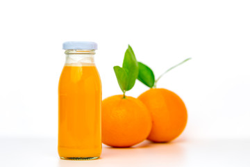 Orange juice in glass bottles with two oranges on white background.