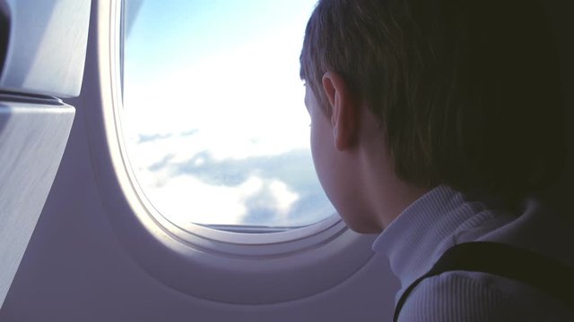 Boy chews gum and looks out the window at the clouds when landing the plane