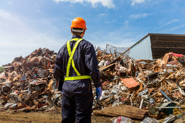 Engineer and recycle. Engineers standing in recycling center. back view of Male foreman wearing protective equipments and holding tablet and looking at  Recyclable material.