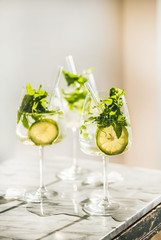 Hugo Sparkling wine cocktail with fresh mint and lime in glasses with eco-friendly straws over white marble kitchen counter, selective focus. Cold refreshing summer alcoholic drink - obrazy, fototapety, plakaty