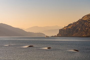 A cargo ship at dusk in the columbia river that serves as a border between the states of Washington and Oregon