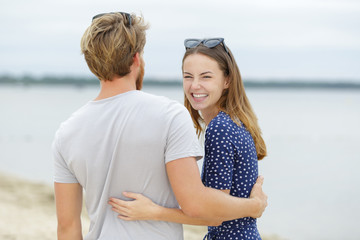 happy couple hugging and laughing together at the beach