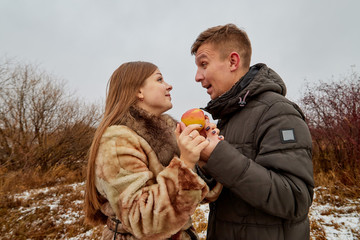 Romantic couple in love on autumn or winter walk with apple