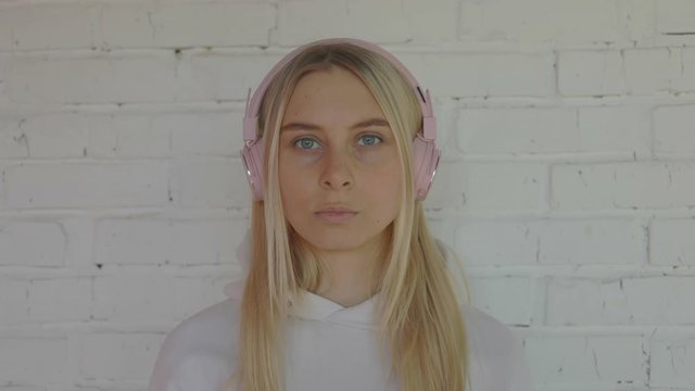 Portrait of stylish caucasian woman in pink headphones in music studio with red wall listen indie hip hop lofi chillhop music at 5g