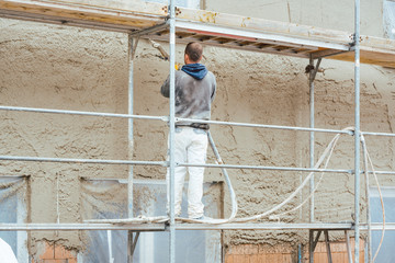 Worker plastering outer wall of newly built house