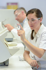 Fototapeta premium woman doctor holding magnifying glass in lab