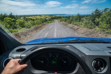 View from behind the wheel of a car on a dirt road in the middle of the expanse stretching into the distance.