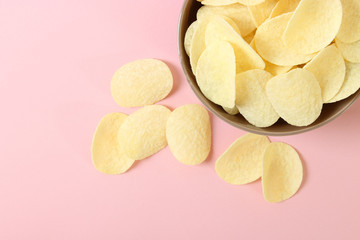 Potato chips in a plate on a colored background top view.